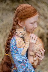 redhead girl holding a ginger kitten in her arms
