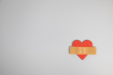 Heart with medical patch on grey background, top view. Relationship problems concept broken heart...