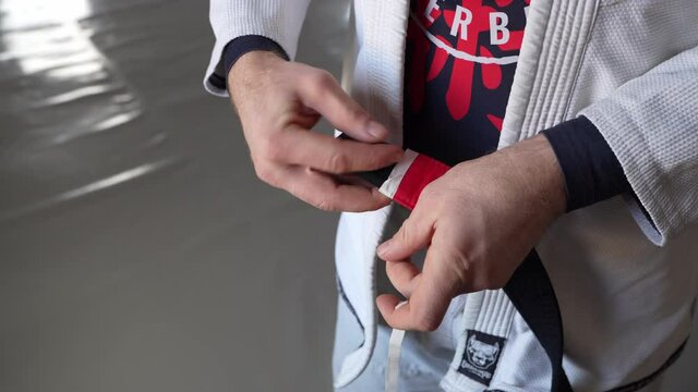 brazilian jiu jitsu bjj black belt male athlete holding belt putting on stripes