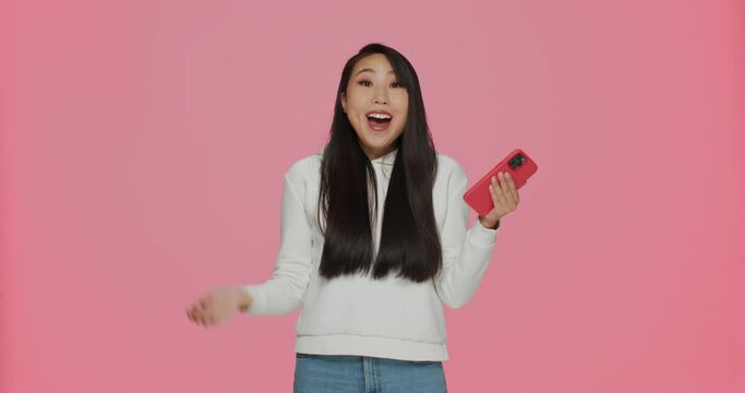 Surprised lucky young asian girl reading good news, win online shopping promo code or prize in social network giveaway