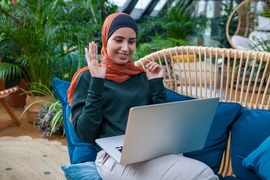 Smiling Woman Wearing Headscarf Having Video Call Via Laptop At Home