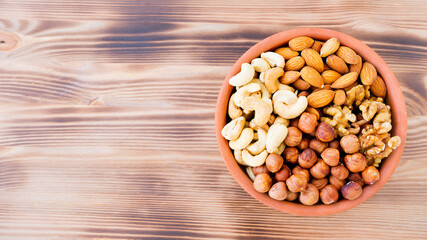 Plate with different nuts on a wooden surface