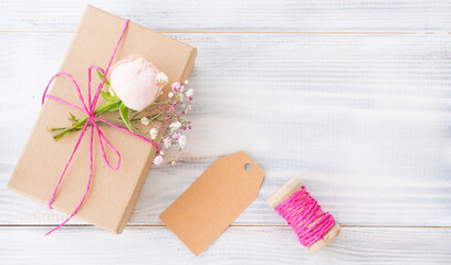 Gift wrapped in a box. The box is decorated with a fresh delicate rose and a sprig of gypsophila