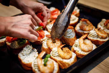 Making Bruschetta with shrimps on a black tray.