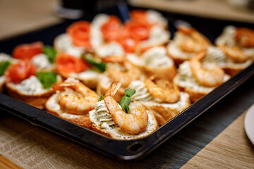 Bruschetta with shrimps on a black tray.
