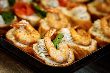 Bruschetta with shrimps on a black tray.