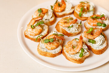Small sandwiches with shrimps on a white plate.