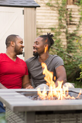 Smiling male couple sitting by fire pit
