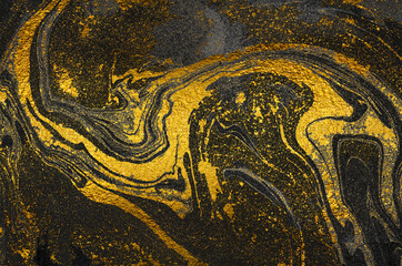 Golden swirl, artistic design. Suminagashi – the ancient art of Japanese marbling. Paper marbling is a method of aqueous surface design. Black and gold paper texture. 