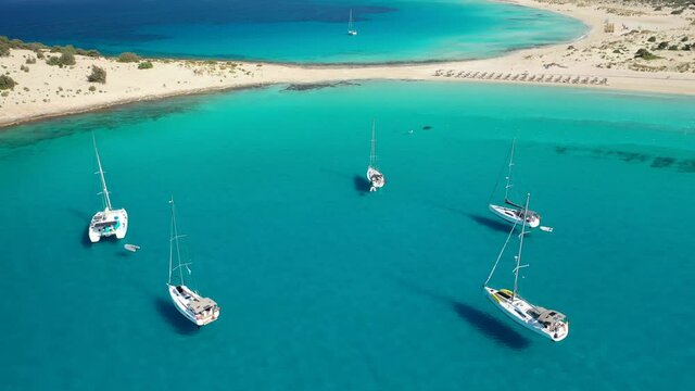 Aerial drone video of paradise turquoise sandy beach and bay of Simos in island of Elafonisos visited by yachts and sail boats, South Peloponnese, Lakonia, Greece