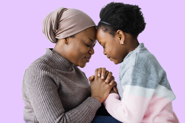 Happy african woman muslim and little child holding hands on violet background in studio . Connection between mother and daughter.