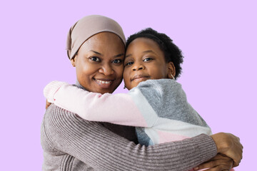 Little female child hugging her pleasant muslim mother on purple background. Happy family smiling and looking at camera.