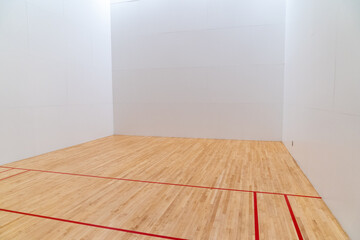 Fototapeta na wymiar Inside a raquetball court, with red markings, white walls and wood floors