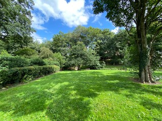 Green parkland, with wooden benches, on a sunny day in, Steeton, Keighley, UK