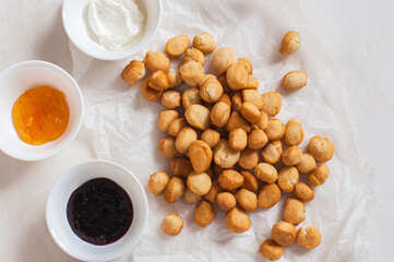 Shi-baursak, Kazakh traditional fried dounuts served on a parchment paper on a white background. Festive sweet baking.