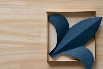 paper fleur-de-lis or fleur-de-lys shape in a box on a wooden surface