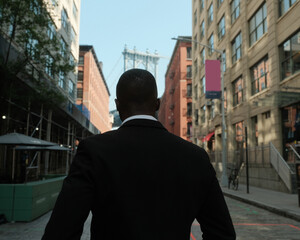 USA, New York City, Rear view of man in suit standing on street - obrazy, fototapety, plakaty