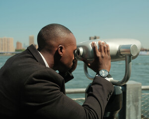 Fototapeta na wymiar USA, New York City, Man in suit looking at city through coin operated binoculars