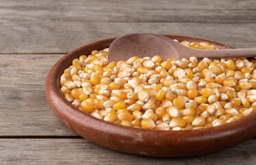 Narrow focus, dried corn or popcorn grains in a plate over wooden table