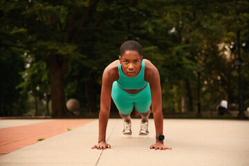 Athlete woman in sports clothing doing push-ups in park