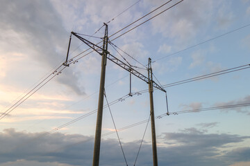 Dark silhouette of high voltage tower with electric power lines at sunrise