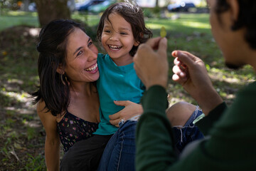 Young Latino parents happily share with their 3 year old son at the park. Family concept.