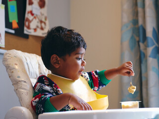 Boy sitting in high chair and eating © Cultura Creative