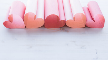 Pink and red paper heart border on a white background with copy space