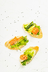 Open sandwiches with salted salmon, cream cheese, salad leaves and sesame seeds. Seafood