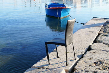 Vecchia sedia sulla banchina del molo. Sud Italia