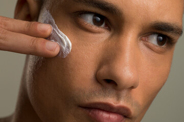 Close-up of man applying face cream - obrazy, fototapety, plakaty