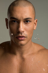 Fototapeta na wymiar Studio portrait of shirtless man splashing water on face