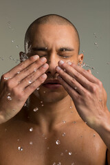 Studio shot of shirtless man splashing water on face