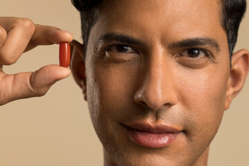 Close-up of man holding nutritional supplement capsule