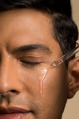Close-up of man applying oil on face