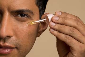 Close-up of man applying oil on face