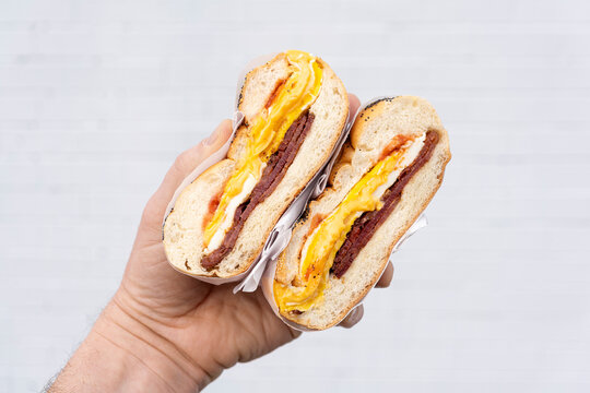 Bacon, Egg and Cheese breakfast sandwich with ketchup. Holding a cross section of great New York deli breakfast sandwich.