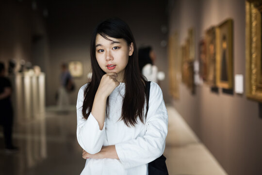 Chinese woman standing in art museum near the painting in baguette