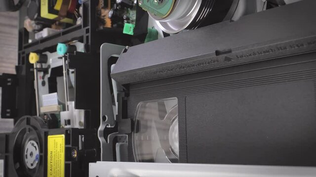 Closeup shot of a vhs cassette and a dvd being removed from a player. Camera slowly moving sideways. Vertical Format Video. 9:16