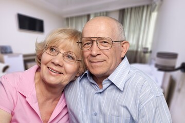 Smiling older couple hugging at home. Happy senior adult mature classy husband and wife