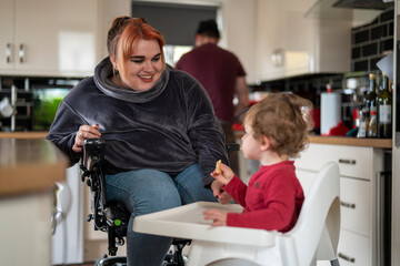 Mother in wheelchair feeding son in high chair