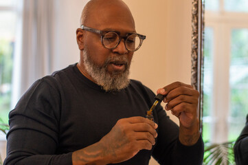 Mature man holding CBD oil bottle © Cultura Creative