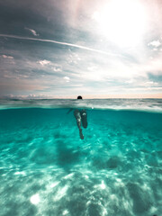 Mujer joven freediver nadando en el cristalino y turquesa mar del caribe, chica en bikini nadando en el mar transparente