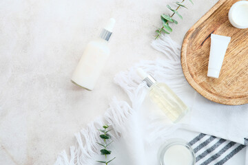 Fototapeta na wymiar Skincare cosmetics in white bottles and containers with green eucalyptus leaves on stone table. Natural organic beauty products design, branding.