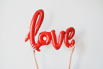 Love red foil balloon in female hands. Happy Valentines Day, Mother's Day, birthday concept.