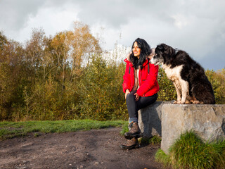 Female hiker with dog sitting on stones and resting