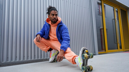 Young man wearing roller skates stretching by iron wall