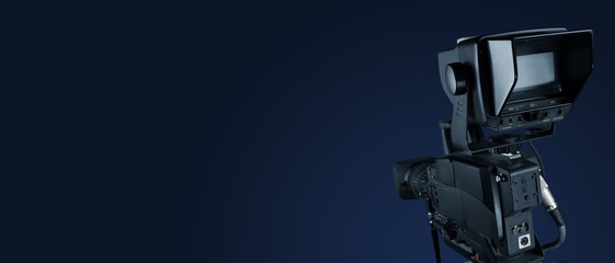 Fototapeta premium Digital film camera in the dark wall background. Video camera for film production,