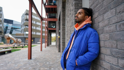Young man wearing blue puffer jacket leaning on wall