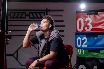 Woman drinking water from bottle in gym